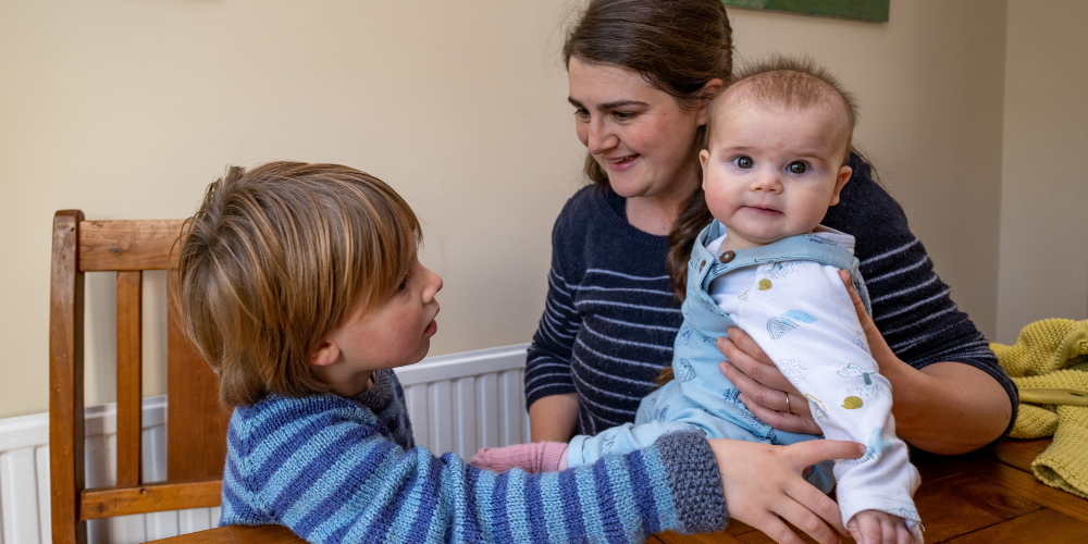 A foster carer sitting at the table with a baby boy and his brother
