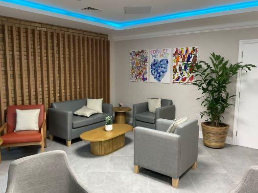 Lounge chairs with small coffee table, plant and picture on a wall in a reception area