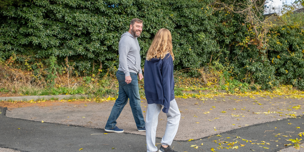 A foster carer walking down the street talking to a young person