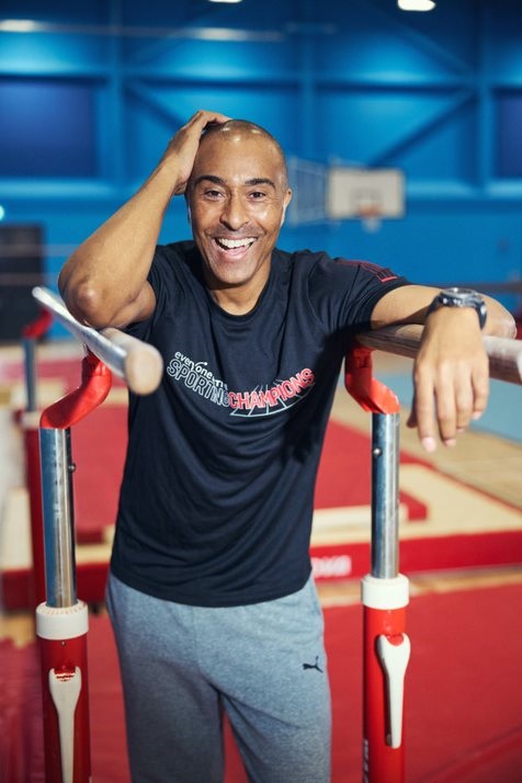 Colin Jackson MBE, standing in a sports hall.