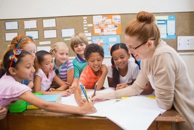 Kids and teacher siting around a table in school