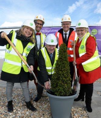 Five individuals taking part in a tree potting ceremony to celebrate Topping Out.