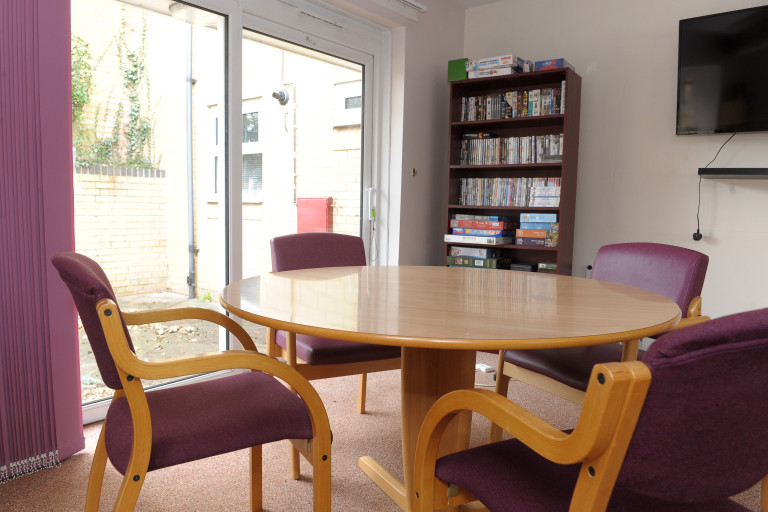 Communal room with round table, chairs, games and TV at Baker Street independent living scheme.