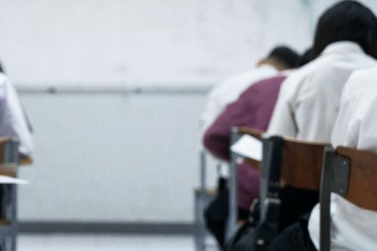 Students taking their exams at desks in a classroom