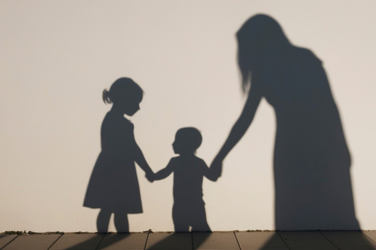 Image of children holding a foster carers hand, silhouetted 