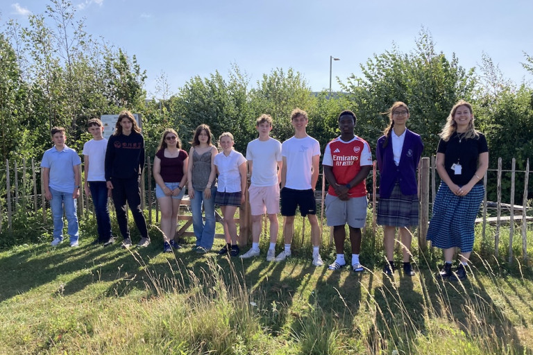 Students stood in front of a thriving Tiny Forest at the student programme celebration event hosted by Cranfield University.