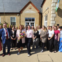 Group photo outside a school building.  Front row: Cllr Liz Childs, Cllr Gareth Mackey, Mrs Stone and Amana Gordon, with school staff behind.