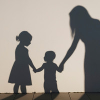 Image of children holding a foster carers hand, silhouetted 